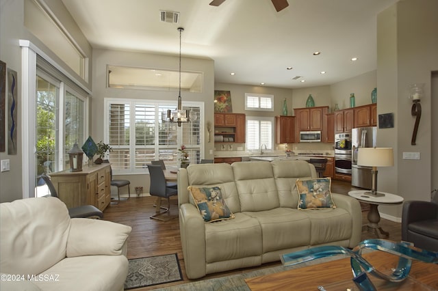 living room featuring dark wood finished floors, baseboards, ceiling fan with notable chandelier, visible vents, and recessed lighting