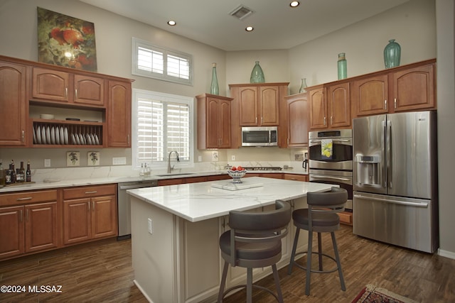 kitchen featuring visible vents, a kitchen island, appliances with stainless steel finishes, a sink, and dark wood-style floors