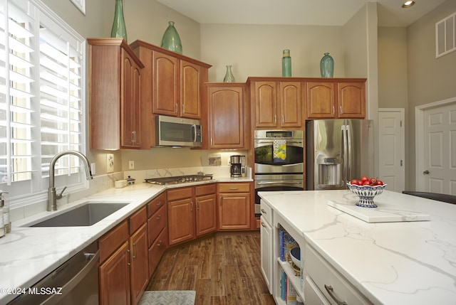 kitchen featuring a sink, appliances with stainless steel finishes, light stone countertops, and dark wood finished floors