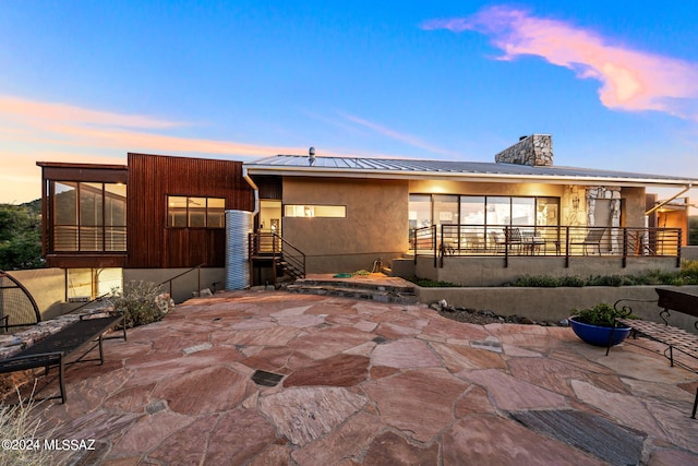 back house at dusk featuring a patio area