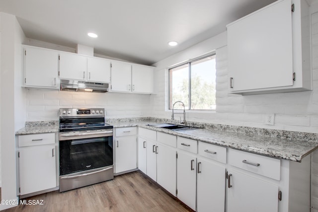 kitchen with sink, backsplash, white cabinetry, electric stove, and light hardwood / wood-style floors