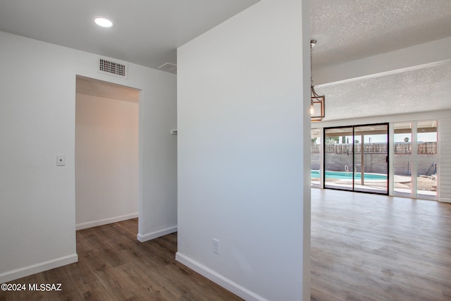 hallway with a textured ceiling and dark hardwood / wood-style flooring