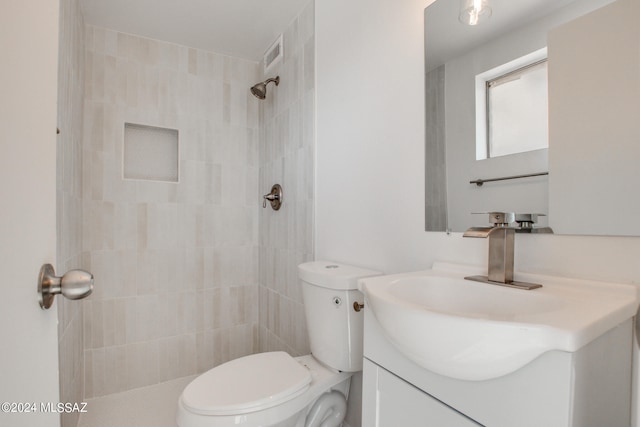 bathroom featuring a tile shower, vanity, and toilet