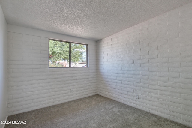 unfurnished room with lofted ceiling, carpet, a textured ceiling, and brick wall