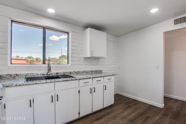 kitchen with dark hardwood / wood-style floors, light stone countertops, white cabinetry, and sink