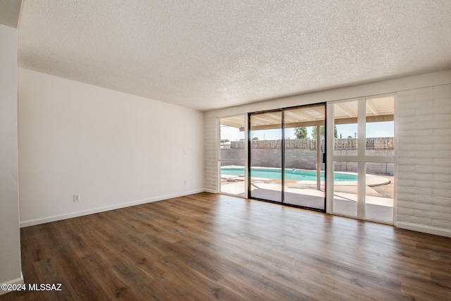 unfurnished room featuring a textured ceiling and dark hardwood / wood-style flooring