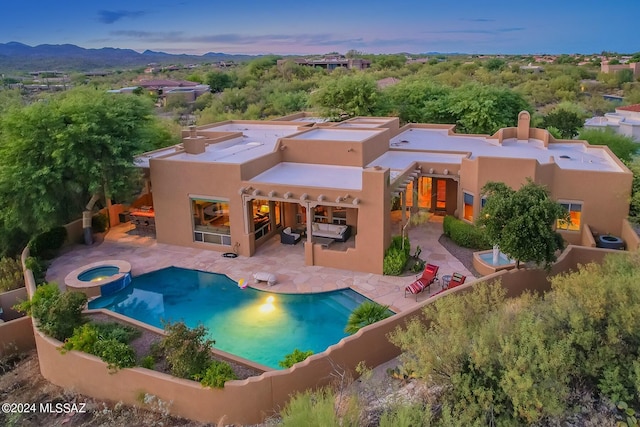 pool at dusk with an in ground hot tub, a patio, a mountain view, and cooling unit