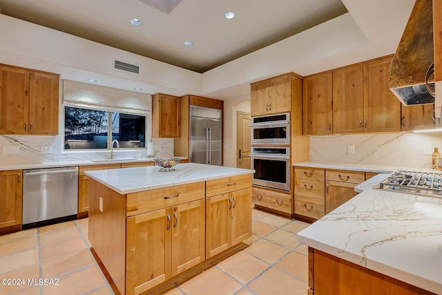 kitchen with tasteful backsplash, ventilation hood, a kitchen island, sink, and appliances with stainless steel finishes