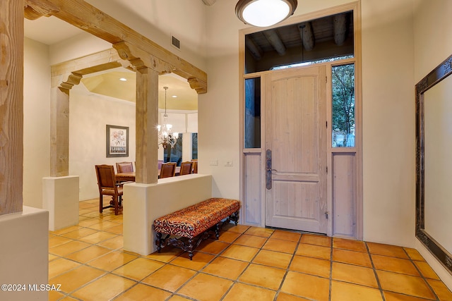 entryway featuring beamed ceiling, an inviting chandelier, and light tile patterned floors