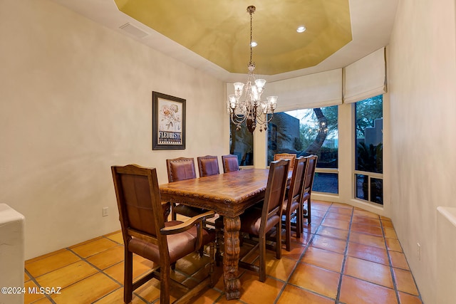 tiled dining area with a notable chandelier and a raised ceiling