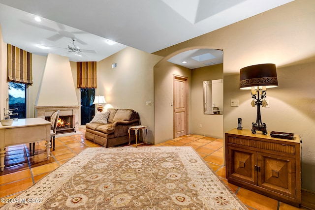 living room featuring light tile patterned flooring, ceiling fan, and a large fireplace