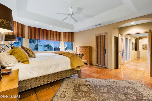 tiled bedroom featuring ceiling fan and a raised ceiling