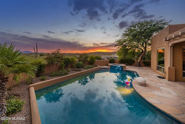 pool at dusk with an in ground hot tub and a patio