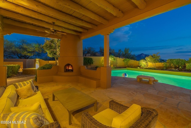 patio terrace at dusk featuring an outdoor living space with a fireplace and ceiling fan