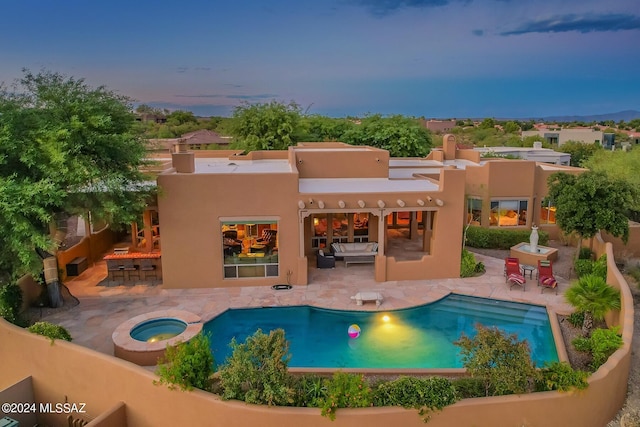 back house at dusk with a patio area and a swimming pool with hot tub