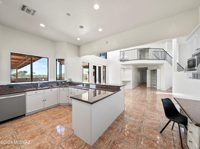 kitchen with kitchen peninsula, appliances with stainless steel finishes, white cabinetry, and sink