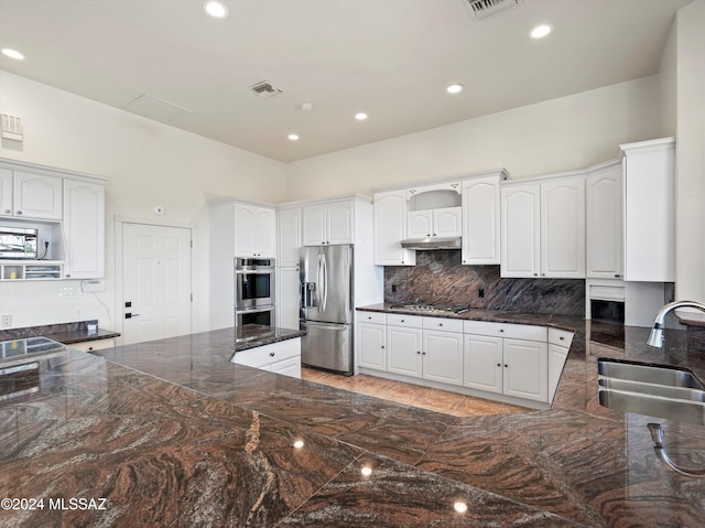 kitchen featuring kitchen peninsula, tasteful backsplash, stainless steel appliances, sink, and white cabinets