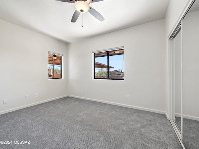 unfurnished bedroom with a closet, dark carpet, and ceiling fan