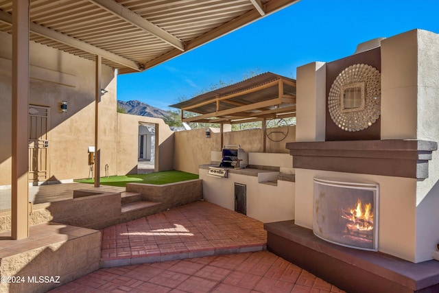 view of patio / terrace featuring a mountain view, area for grilling, grilling area, and exterior fireplace