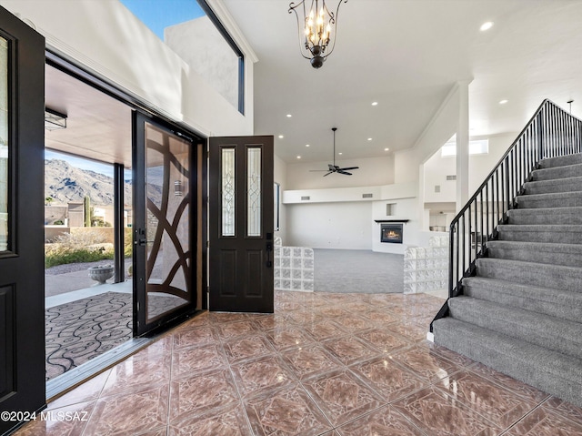 foyer entrance featuring a mountain view, a towering ceiling, and ceiling fan with notable chandelier