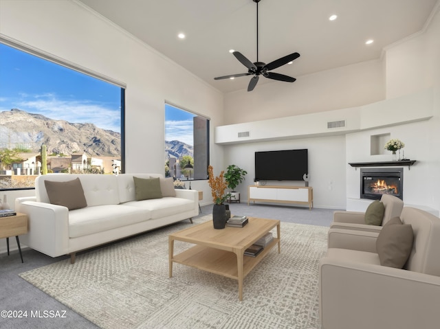 living room with a mountain view, ceiling fan, crown molding, and light carpet