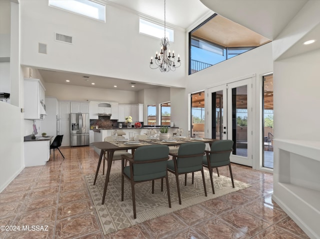 dining room featuring french doors, a towering ceiling, plenty of natural light, and a notable chandelier