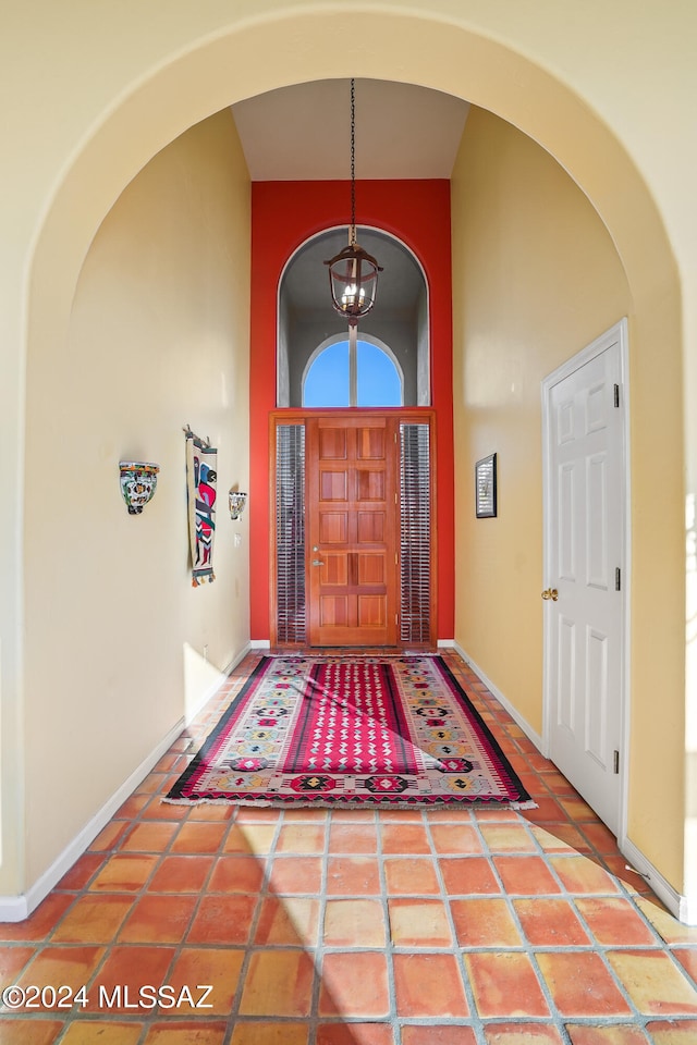 tiled entrance foyer with a notable chandelier and a towering ceiling