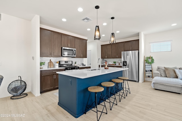 kitchen featuring decorative backsplash, light hardwood / wood-style floors, appliances with stainless steel finishes, and pendant lighting