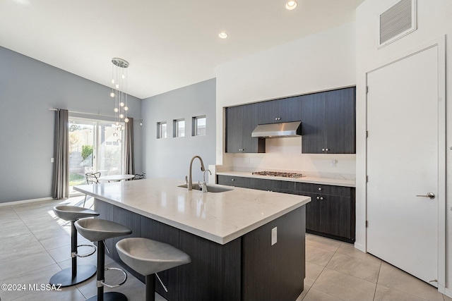 kitchen with sink, an island with sink, decorative light fixtures, and vaulted ceiling