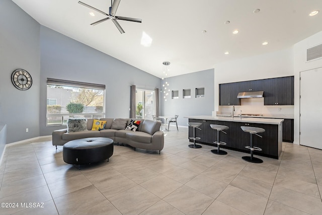 tiled living room featuring ceiling fan, sink, and high vaulted ceiling