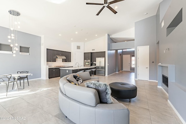 tiled living room with ceiling fan, sink, and high vaulted ceiling