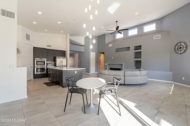 tiled dining area with ceiling fan, sink, built in features, and a high ceiling