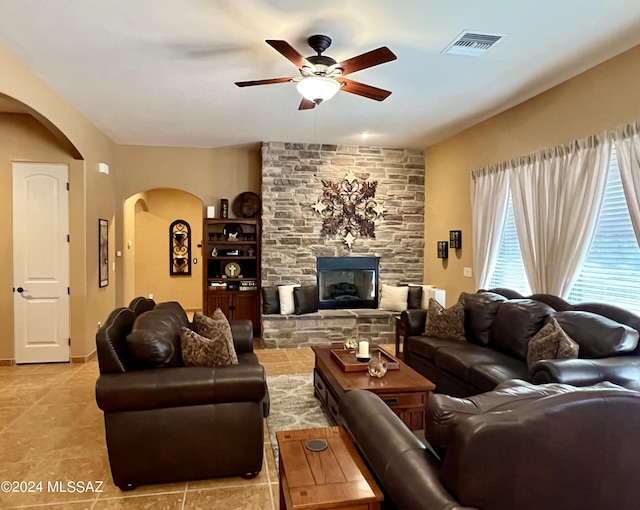 living room with a stone fireplace and ceiling fan