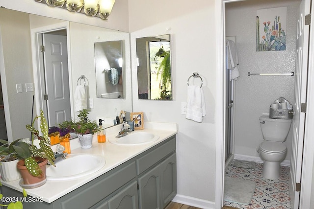 bathroom featuring double vanity, toilet, baseboards, and a sink