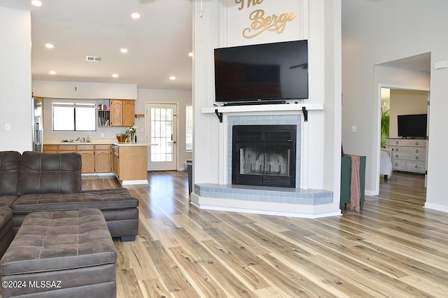 living room featuring visible vents, baseboards, recessed lighting, a fireplace, and light wood-style floors