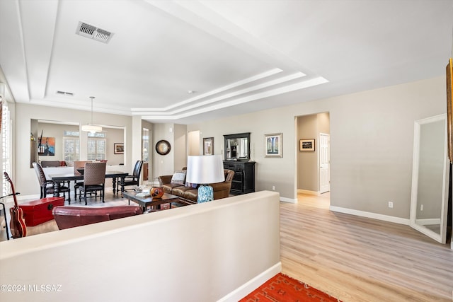 living room featuring light wood-type flooring and a tray ceiling