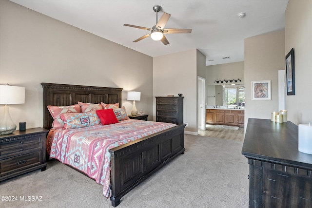 bedroom featuring light carpet, ceiling fan, and ensuite bathroom