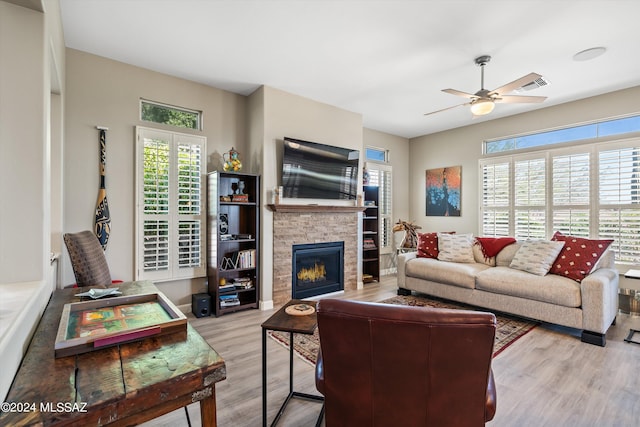 living room with ceiling fan, a fireplace, and light hardwood / wood-style floors