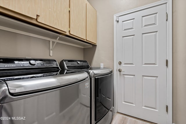 clothes washing area with cabinets, light hardwood / wood-style floors, and washer and clothes dryer