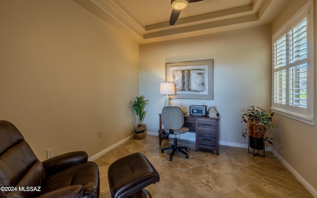 home office featuring ceiling fan and a tray ceiling