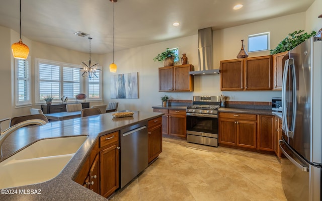 kitchen with sink, wall chimney exhaust hood, decorative light fixtures, stainless steel appliances, and a chandelier