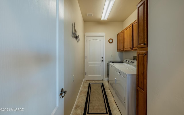 washroom featuring washing machine and clothes dryer and cabinets