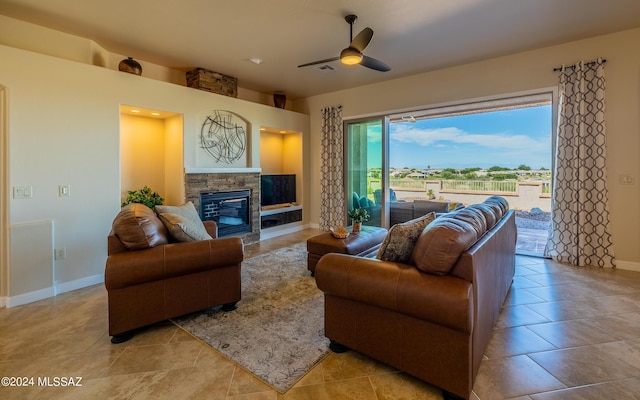 living room with a stone fireplace, ceiling fan, and light tile patterned floors