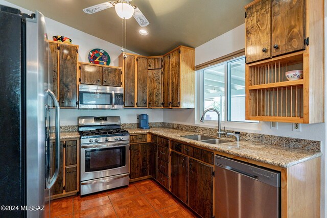 kitchen featuring a sink, light stone counters, pendant lighting, and stainless steel dishwasher