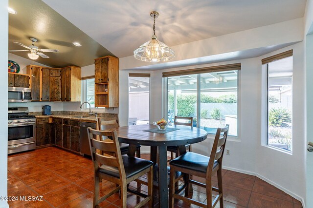 dining room with vaulted ceiling, baseboards, and ceiling fan with notable chandelier