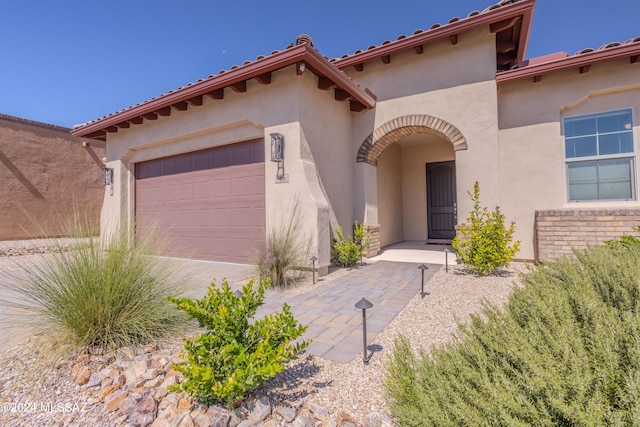 mediterranean / spanish house featuring a garage, stucco siding, and driveway