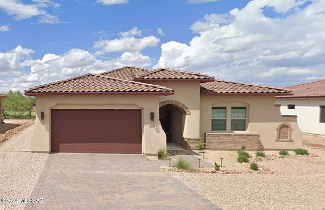 mediterranean / spanish house with a tile roof, driveway, a garage, and stucco siding