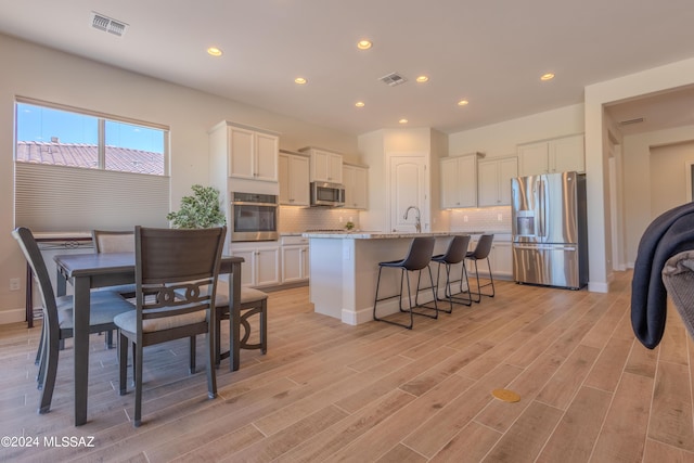 kitchen featuring backsplash, visible vents, white cabinetry, and stainless steel appliances
