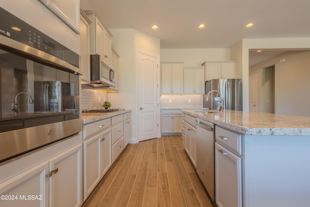 kitchen featuring white cabinetry, a center island with sink, light hardwood / wood-style flooring, and appliances with stainless steel finishes