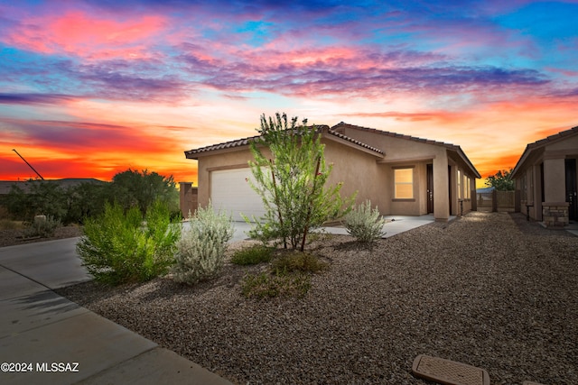 view of front of property featuring an attached garage, a tile roof, concrete driveway, and stucco siding